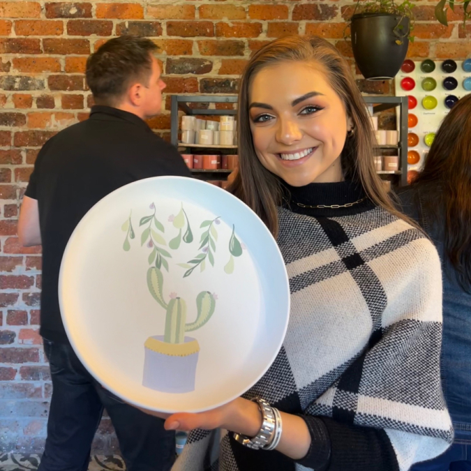Happy customer holding painted pottery piece at Clay Cafe Hout Bay, ideal for family-friendly activities.