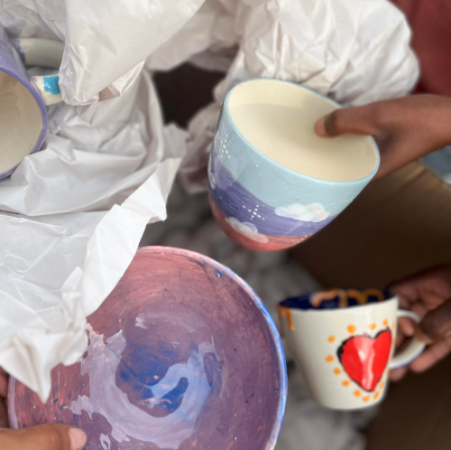 Completed pottery pieces from a Clay Cafe Paint and Donate event, featuring colourful and handcrafted designs supporting local charities.