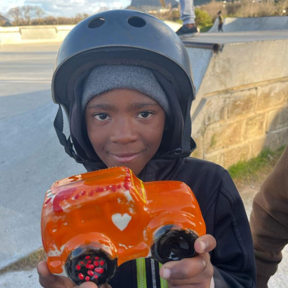 A child from a local charity happily holding their new pottery piece from Clay Café’s Paint & Donate programme.