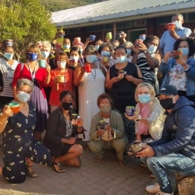 A group photo of participants with their pottery pieces after attending painting at a Paint and Donate fundraiser.