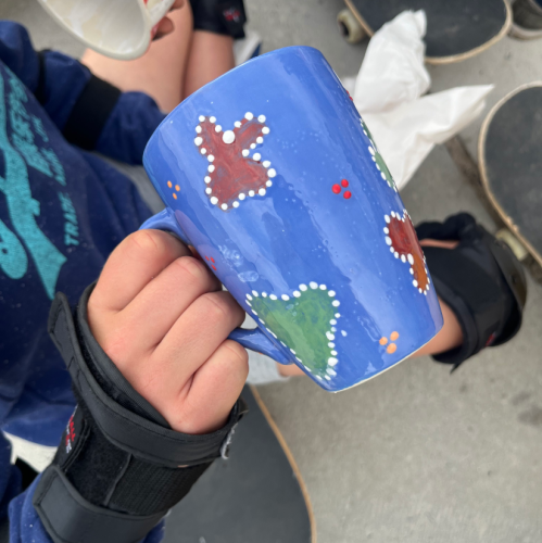 Close-up of a pottery piece being painted during a Paint and Donate event at Clay Café.